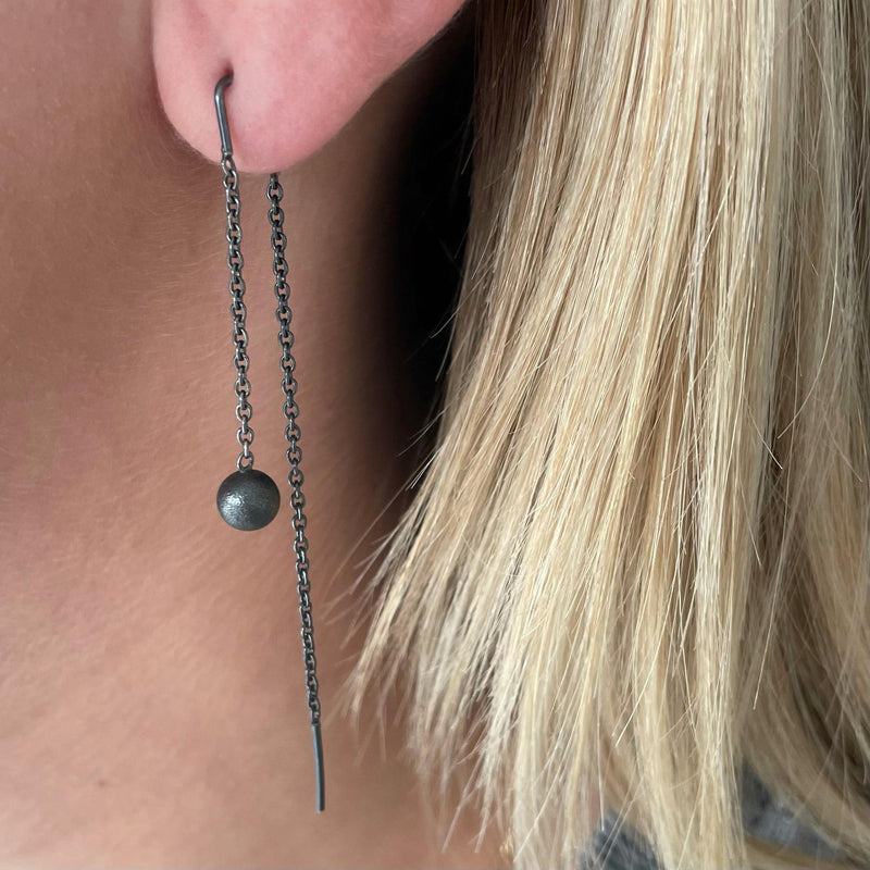 Asymmetrical earrings with bullet